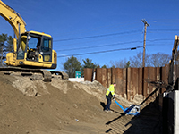 Backhoe drops dirt behind abutment 1.